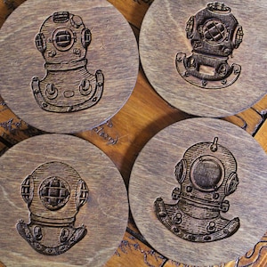 May include: Four wooden coasters with a circular design featuring an engraved image of a vintage diving helmet. The coasters are made of dark brown wood and have a rustic appearance.