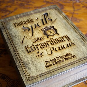 May include: A wooden box with a brown stain and a black engraved design. The box has the text "Fantastic Spells and Extraordinary Potions" and "Big Book of Incredible Ideas & Magical Memories".