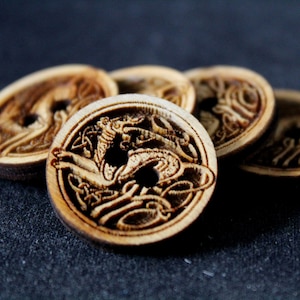 May include: Five wooden buttons featuring a Celtic knot design with a dragon in the centre. The buttons are brown and have a hole in the centre.
