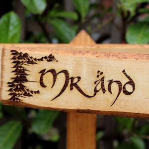 May include: A wooden sign with the words "Mr. and Mrs." burned into the surface. The sign is decorated with a design of trees and mountains.