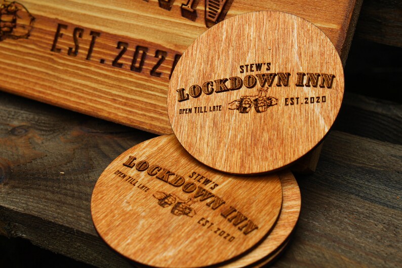 May include: Four wooden coasters with the text "STEW'S LOCKDOWN INN" and "OPEN TILL LATE" and the year "EST. 2020" engraved on them.