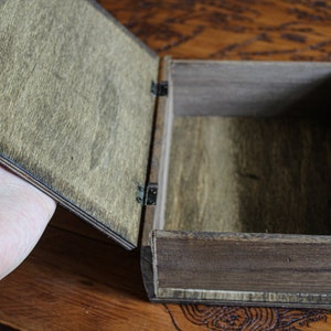 May include: A wooden box with a hinged lid, open to reveal the empty interior. The box is made of dark brown wood with a natural wood grain.