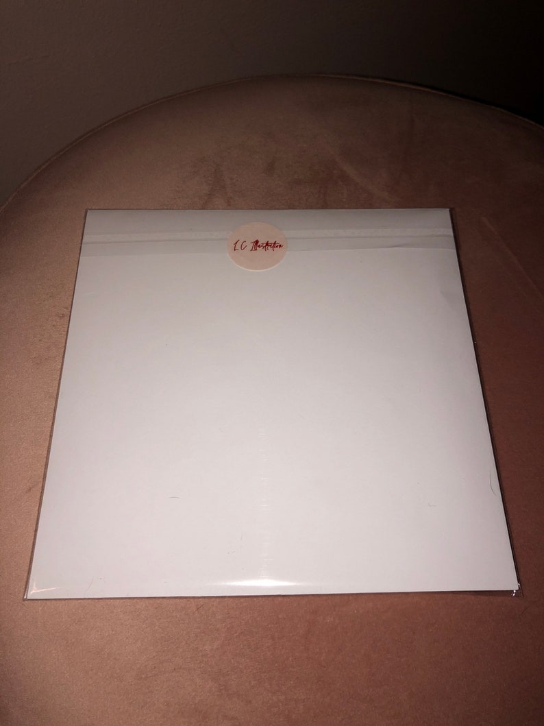 May include: A white, rectangular piece of paper with a round, white sticker in the upper right corner. The sticker has red text that reads "LC Bella".