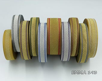 May include: A collection of decorative ribbons in various colors, including gold, silver, and white. The ribbons feature patterned designs and stripes. The text "EMMA 193" is visible at the bottom.