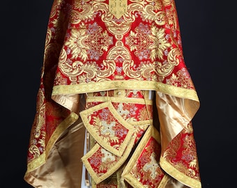 May include: A red and gold liturgical vestment with intricate embroidery and a white undergarment.