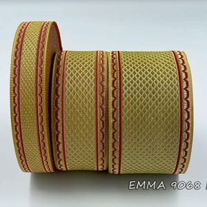 Puede incluir: Cuatro carretes de cinta de adorno dorada y roja. La cinta tiene un patrón de diamante y un borde festoneado. El texto "EMMA 9068 No.05" está impreso en la parte inferior de la imagen.