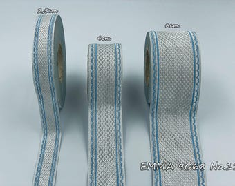Puede incluir: Tres rollos de cinta con estampado plateado y azul. La cinta tiene 2,5 cm, 4 cm y 6 cm de ancho. La cinta tiene un patrón de diamante con un borde azul. El texto "EMMA 9068 No.11" está impreso en la parte inferior de la imagen.