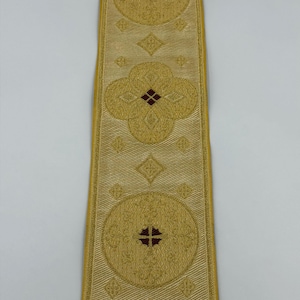 May include: Gold-colored decorative ribbon with repeating circular and floral patterns. The ribbon has a textured appearance and features a cross design in the center of the circles. The text "EMMA 253 No.3" is printed on the ribbon.