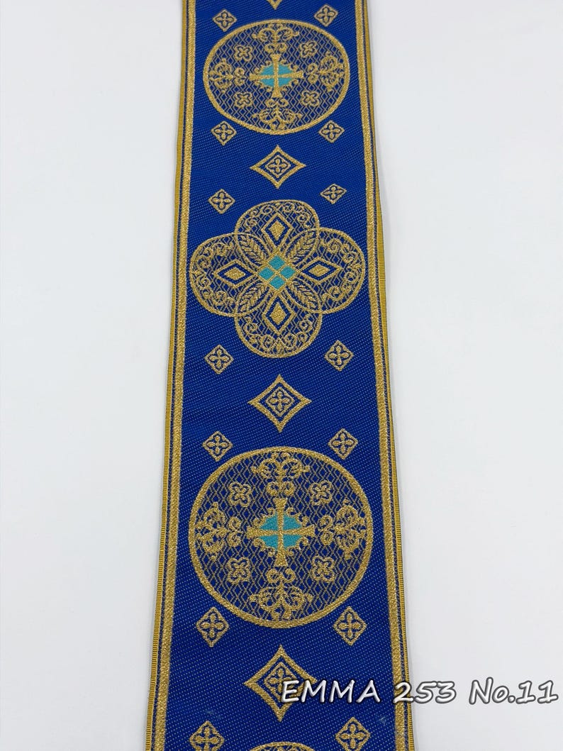 May include: A blue ribbon with gold filigree designs and turquoise accents. The ribbon features repeating circular and diamond patterns. The text "EMMA 253 No.11" is printed on the ribbon.