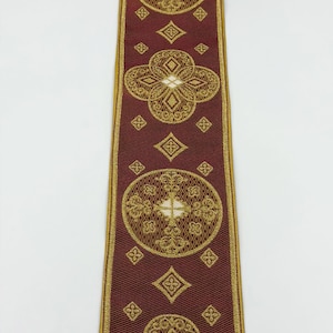 May include: Burgundy ribbon with gold embroidered floral and geometric patterns. The ribbon features repeating circular and diamond shapes, with the text "EMMA 253 No.9" at the bottom. The edges are trimmed with gold.
