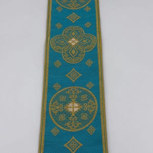 May include: A teal ribbon with gold floral patterns and borders. The ribbon features repeating circular, diamond, and quatrefoil designs. The text "EMMA 253 No.10" is printed in gold at the bottom of the ribbon.