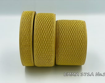 Op de afbeelding: Drie rollen gouden trim met een textuurpatroon. De trim is geëtiketteerd met "EMMA 171A No.2".