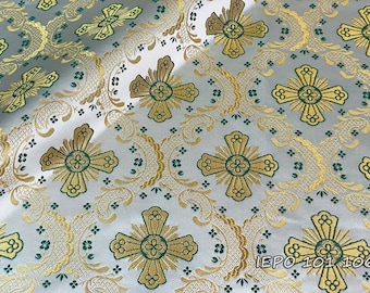 May include: White fabric with a repeating pattern of gold and green crosses. The crosses have a floral design in the center. The fabric has a subtle sheen.