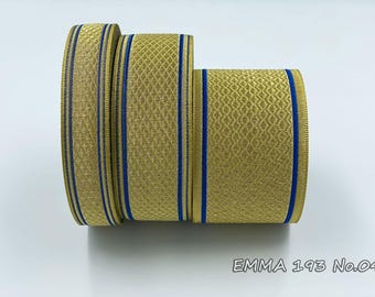 Puede incluir: Tres rollos de cinta de rayas doradas y azules. La cinta tiene un patrón texturizado y está ribeteada con una fina línea azul. La cinta está etiquetada como "EMMA 193 No.04".