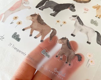 May include: A sheet of transparent stickers featuring watercolor illustrations of horses and a unicorn. The stickers are in various shades of brown, gray, and pink, with floral and foliage accents. The text "31 Transparent Stickers" is visible.