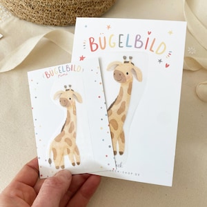 Puede incluir: Dos parches termoadhesivos con un diseño de jirafa. Los parches son de color marrón claro con manchas marrones oscuras y están sobre tarjetas blancas. Las tarjetas tienen el texto "BÜGELBILD" y "Mini" impreso, junto con estrellas y puntos de colores.
