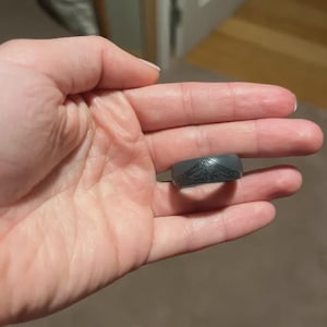 May include: A dark grey silicone ring with a mountain design.