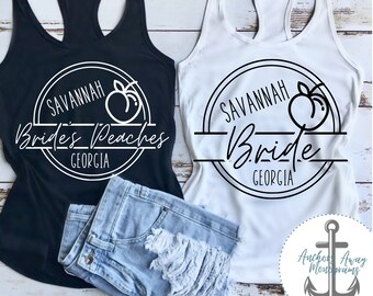 Può includere: Due canottiere bianche con testo nero e una grafica di pesca. Il testo sulla canottiera di sinistra recita "Savannah Brides Peaches Georgia". Il testo sulla canottiera di destra recita "Savannah Bride Georgia".