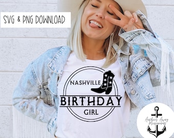 May include: A white t-shirt with a black circle design that says "Nashville Birthday Girl" with a black boot with white stars inside the circle.