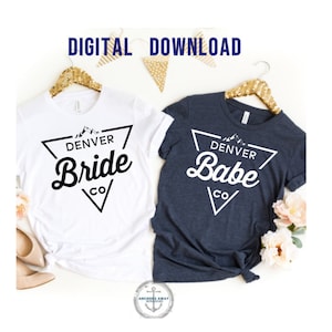 May include: Two t-shirts with a triangle design featuring the text "Denver Bride CO" and "Denver Babe CO" in a retro font. The shirts are white and navy blue.