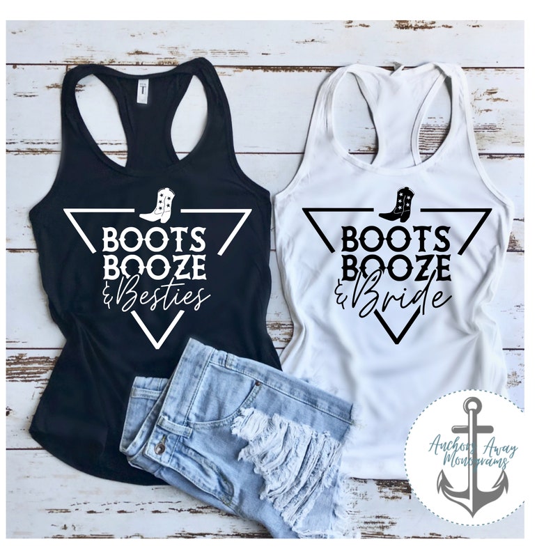 Puede incluir: Dos camisetas sin mangas negras y blancas con un dise&ntilde;o de tri&aacute;ngulo y el texto "Boots Booze & Besties" y "Boots Booze & Bride". Las camisetas sin mangas est&aacute;n sobre una superficie de madera con un par de pantalones cortos de mezclilla azul.