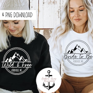 May include: Two black and white mountain range designs with text. One design says "Wild & Free" with "Asheville, NC" below. The other design says "Bride to Be" with "Asheville, NC" below.