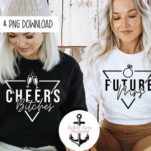 May include: Two white sweatshirts with black text and graphics. One sweatshirt says "Cheers Bitches" with a graphic of two champagne glasses. The other sweatshirt says "Future Mrs." with a graphic of a diamond ring.