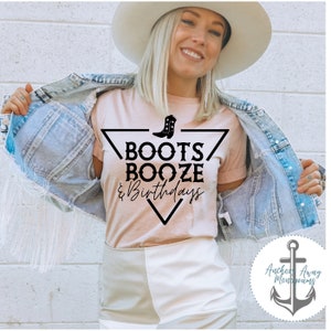 Peut inclure: T-shirt rose clair avec l'inscription noire "BOOTS, BOOZE, & Birthdays" et une botte de cowboy. La chemise est port&eacute;e avec une veste en jean et un short blanc.