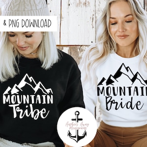 May include: Two people wearing black and white sweatshirts with a mountain range graphic and the text "Mountain Tribe" and "Mountain Bride".