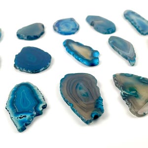 May include: Assortment of blue agate slices, each with unique patterns and shapes. The slices are smooth and polished, with a variety of shades of blue.