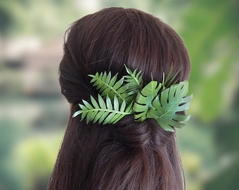 May include: A green leafy hair accessory with a tropical plant design. The accessory is made of artificial leaves and is worn in a woman's hair.