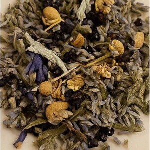 Pode incluir: Close-up de uma mistura de ervas e flores secas. A mistura inclui lavanda, camomila e outras plantas em tons de roxo, verde e bege. A imagem mostra a textura e variedade dos ingredientes, sugerindo uma mistura de chá de ervas.