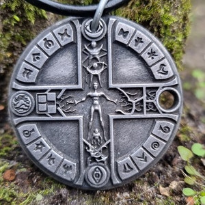 May include: A silver-toned pendant necklace with a circular design featuring a cross with a human figure in the centre. The cross is surrounded by a circle of symbols and runes.