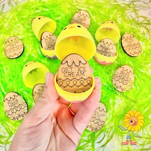 May include: A collection of Easter-themed wooden egg decorations with various activity phrases, including "Get Ice Cream" and "Bake Cookies." The eggs are nestled in yellow chick-shaped containers and arranged on green decorative grass.