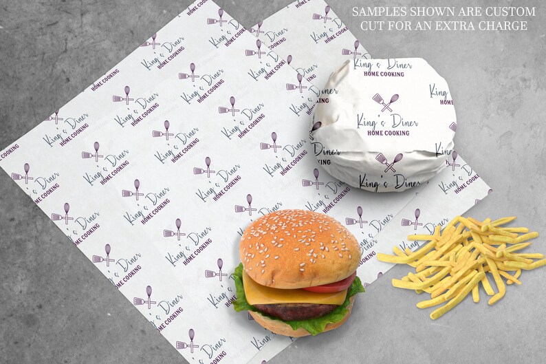 Peut inclure: Papier blanc avec un motif r&eacute;p&eacute;t&eacute; d'un logo violet qui dit "King's Diner Home Cooking" avec un design de cuill&egrave;re et de spatule violet. Un hamburger envelopp&eacute; dans le papier avec un fond blanc et le m&ecirc;me logo. Le hamburger a un pain aux graines de s&eacute;same, de la laitue, de la tomate et du fromage. Un tas de frites sur une surface grise.