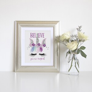 May include: A framed print with a unicorn illustration and the text "BELIEVE you are magical". The unicorn has a silver horn, purple flowers, and rainbow mane. The background is white.