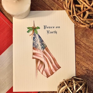 May include: A Christmas card with a watercolor illustration of an American flag draped over a pole with holly and berries. The text "Peace on Earth" is written in a decorative font.