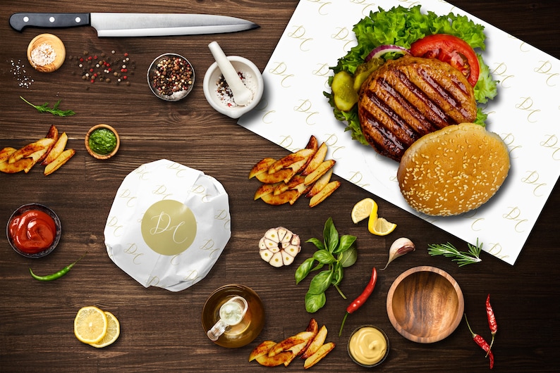 Pu&ograve; includere: Primo piano di un hamburger su carta bianca con le lettere "DC" ripetute. L'hamburger &egrave; composto da un panino con semi di sesamo, un hamburger grigliato, lattuga, pomodoro e un cetriolo. Ci sono anche patatine fritte, aglio, erbe e spezie su una superficie di legno.