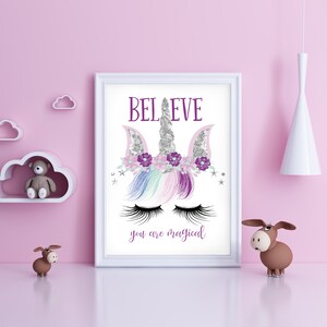 May include: A white framed print with a unicorn illustration. The unicorn has a silver horn, purple flowers, and pink and blue hair. The text "BELIEVE you are magical" is printed below the unicorn.