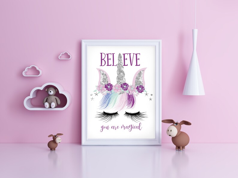 May include: A white framed print with a unicorn illustration. The unicorn has a silver horn, purple flowers, and pink and blue hair. The text "BELIEVE you are magical" is printed below the unicorn.