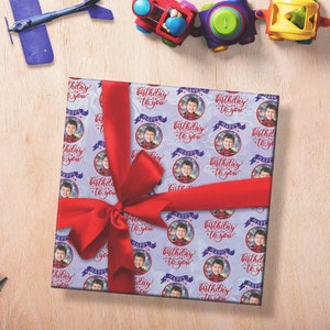 May include: A purple and white gift wrap with a repeating pattern of circles containing a photo of a child and the text "Happy Birthday to You".