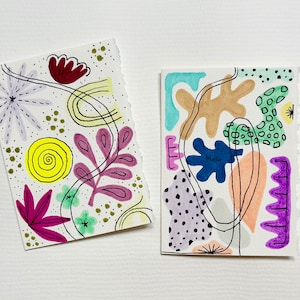 May include: Two abstract art cards with colorful shapes and lines. The first card features a purple flower, a yellow spiral, and pink leaves. The second card features a blue shape with the word "Hello" inside, a brown shape, and a purple shape.