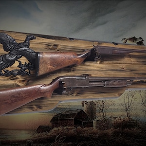May include: Wooden gun rack with two firearms. The rack is made of stained wood and features a decorative black eagle. The firearms are a shotgun and a rifle, both with wooden stocks. The background is a landscape painting.