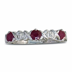 Puede incluir: Un anillo de banda de plata con piedras de rubí rojo y diamantes transparentes alternados.