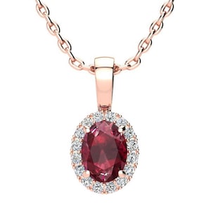 May include: Rose gold pendant necklace featuring an oval, deep red gemstone surrounded by a halo of small, clear gemstones. The pendant hangs from a delicate rose gold chain, creating a classic and elegant jewelry piece.