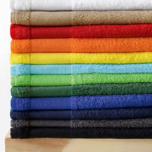 May include: A stack of colourful towels in various shades of white, beige, red, orange, yellow, light blue, green, dark green, blue, navy blue, grey, and black.