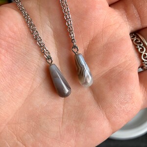 Peut inclure: Deux cha&icirc;nes en argent avec des pendentifs en agate grise. Les pierres sont en forme de larme et pr&eacute;sentent un motif marbr&eacute; blanc et gris.