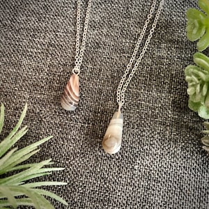 Peut inclure: Deux colliers en argent avec des pendentifs en agate en forme de larme. Les pendentifs sont de couleur brun clair avec des tourbillons blancs et gris.