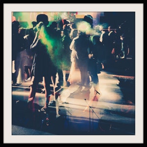 Peut inclure: Un groupe de personnes dansant dans une pièce faiblement éclairée. Les personnes sont en silhouette contre une source de lumière vive, créant un effet brumeux. La pièce est décorée de quelques lumières et il y a des microphones sur des pieds au premier plan.