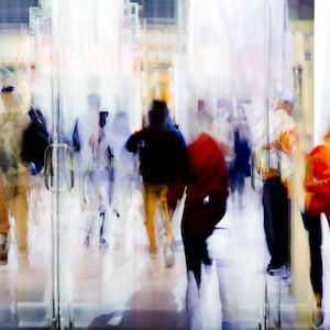 Peut inclure: Une image floue de personnes marchant à travers une porte en verre. Les personnes portent des vêtements variés, dont des vestes, des manteaux et des pulls. L'image est prise d'un angle bas, regardant les personnes de bas en haut.